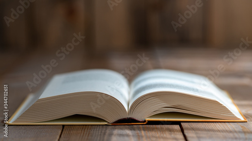 A thick book with open hardcover on a wooden floor © isayurtsever