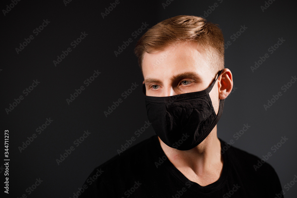 Handsome man in black t-shirt wear black medical mask, gray background. Coronavirus covid-19 quarantine period concept. Handsome man in black t-shirt wear black medical mask, gray background. Coronavirus covid-19 quarantine period concept.