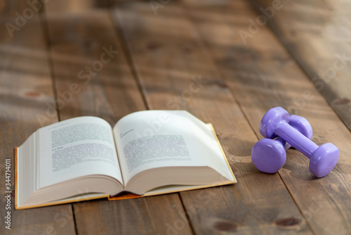 Sports improve the body, books improve the brain, stay home do sports read books, books and dumbbells on wooden floors