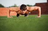 Outdoor sport, fitness training. Handsome Young Men Doing Pushups Outdoors in the Sport Field on a Sunny day