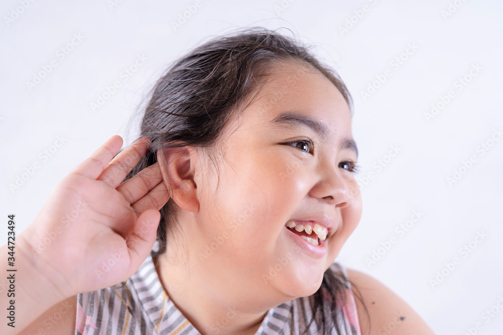 Little asian girl holds her hand near her ear and listening something Little asian girl holds her hand near her ear and listening something