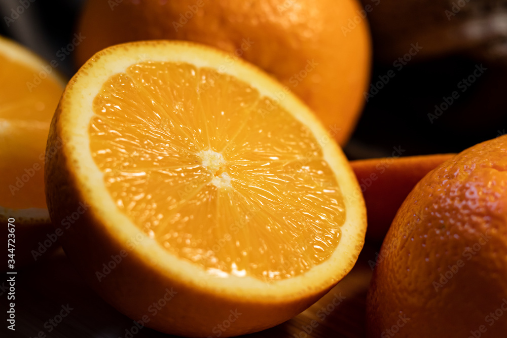 Sliced orange citrus fruit on a wooden board on a dark background. Sliced orange citrus fruit on a wooden board on a dark background.