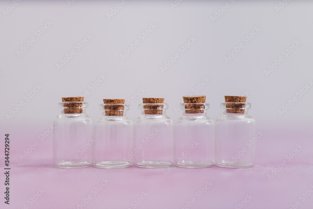 skincare and beauty, group of essential oil bottles on pink and white muted background with minimalist composition