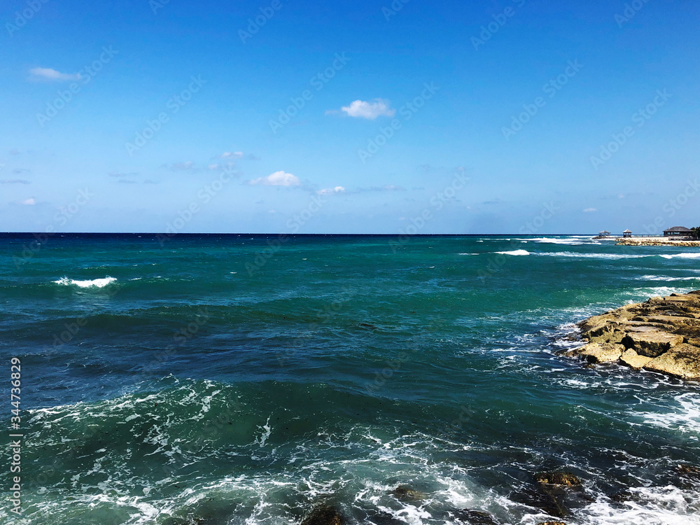 Green ocean waves breaking over rocks on the coast of Jamaica during relaxing winter vacation to islands.