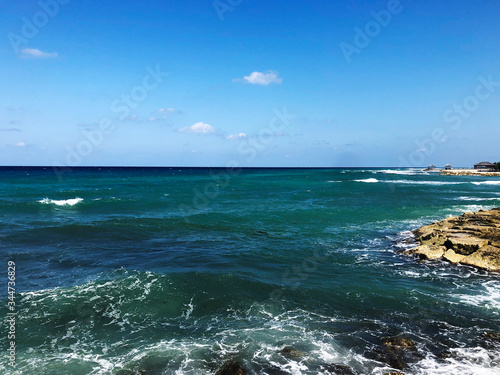 Green ocean waves breaking over rocks on the coast of Jamaica during relaxing winter vacation to islands.
