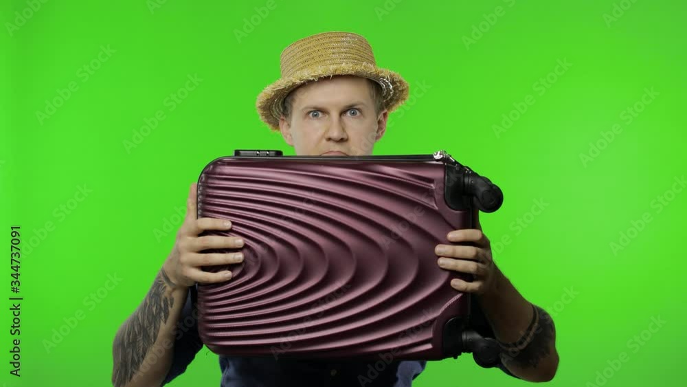 Portrait of man tourist hides behind a suitcase and looks out. Chroma key Portrait of man tourist hides behind a suitcase and looks out. Chroma key
