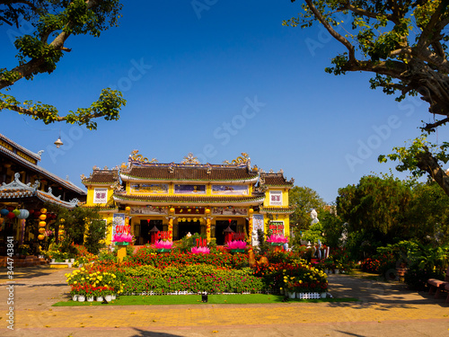 HOIAN, VIETNAM, SEPTEMBER, 04 2017: View of an ancient temple with a beautiful jarden with colorful flowers at hoian, in a sunny day in Vietnam photo