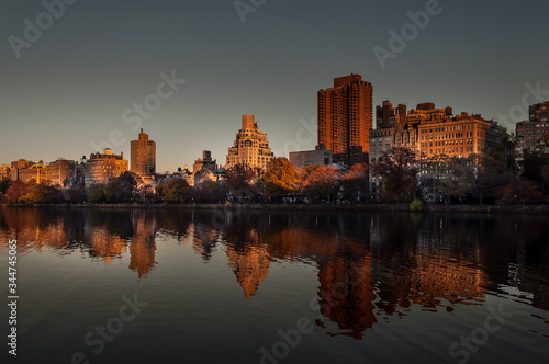 Central Park, New York, USA. Jacqueline Kennedy Onassis Reservoir lake covered in the sunset light. Manhattan buildings in the background and reflection in the water in the foreground.  © Maya K.