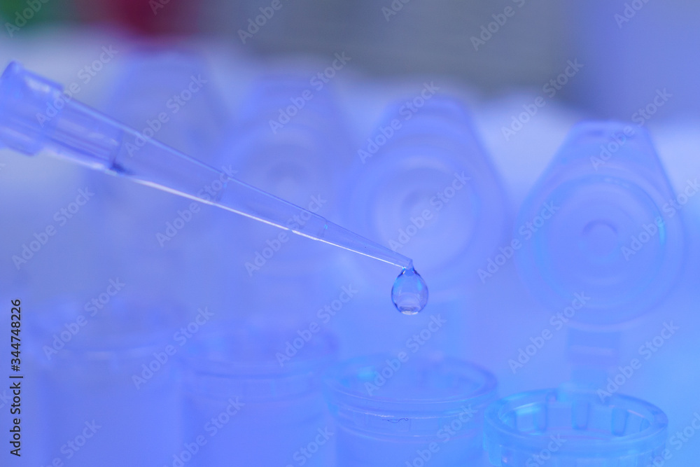 Medical equipment. Pipette adding fluid to one of several test tubes . Medical equipment. Pipette adding fluid to one of several test tubes .
