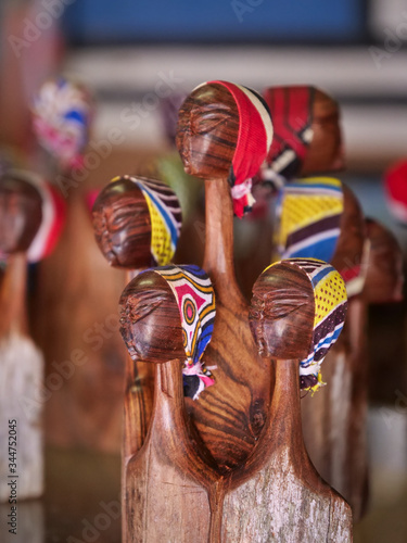 Miniature head scarves on carved wooden heads.