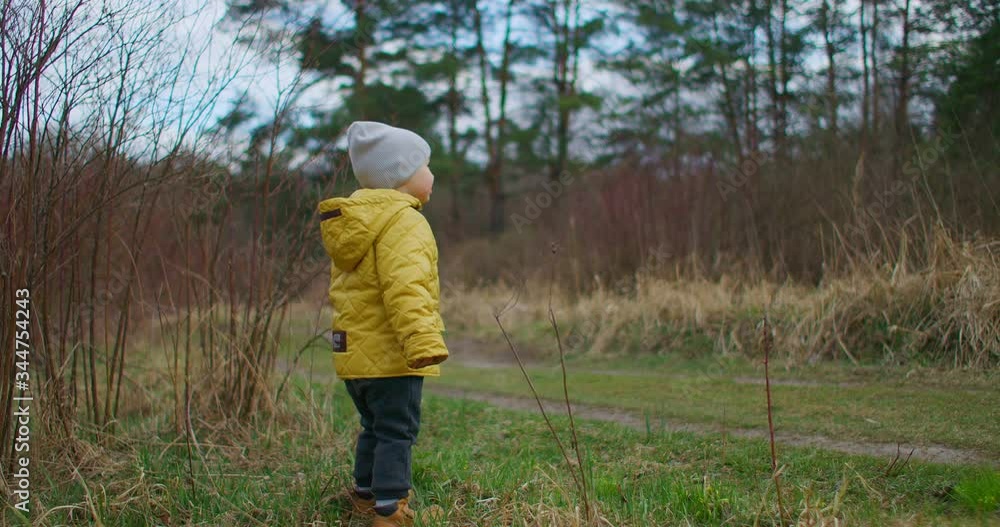 Slow motion. A boy in a yellow jacket stands and looks at the beauty of the forest and the planet earth. Watch and dream about the future. A boy looking into the distance Slow motion. A boy in a yellow jacket stands and looks at the beauty of the forest and the planet earth. Watch and dream about the future. A boy looking into the distance