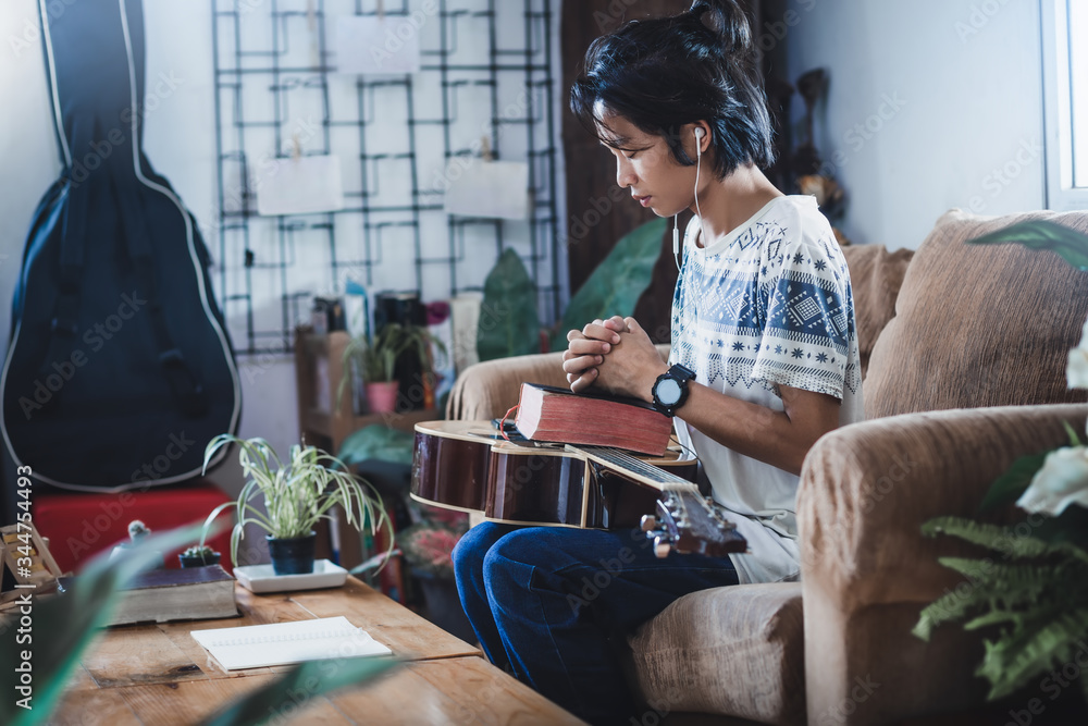 Φωτογραφία Young male learning the Bible and praying at home on sofa in morning, Christians should worship and thank God, Christian worship concept