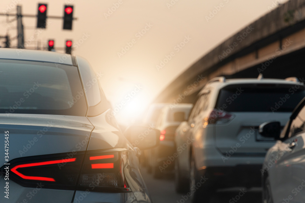 Traffic conditions on the road. Back side of white car open brake light. Car attached to a red traffic light at an intersection beside a multi-level bridge.