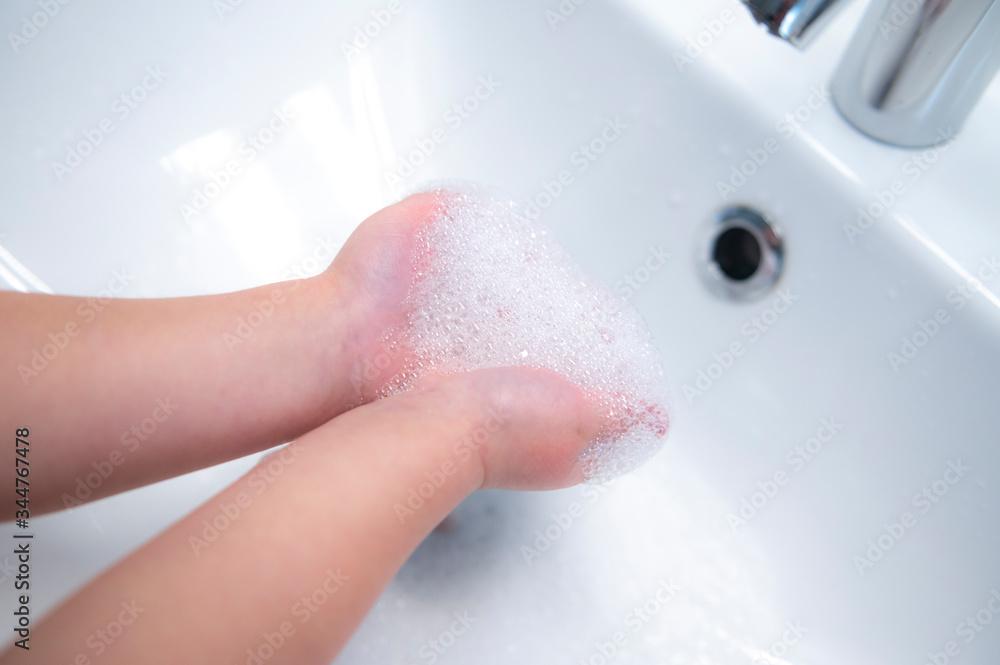 Fototapeta premium Child washing hands with soap to fight covid-19