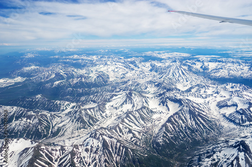 Russia. Kamchatka peninsula. The view from the porthole of the aircraft on the snowy peaks of volcanoes.