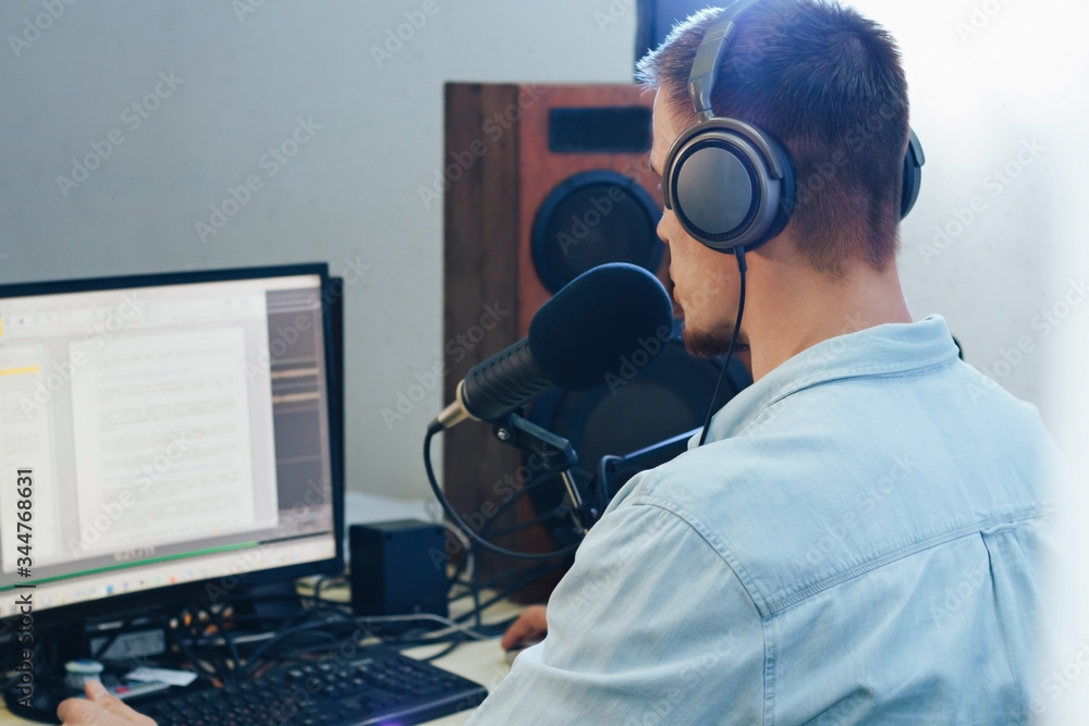 A young male radio host with headphones in front of a microphone A young male radio host with headphones in front of a microphone