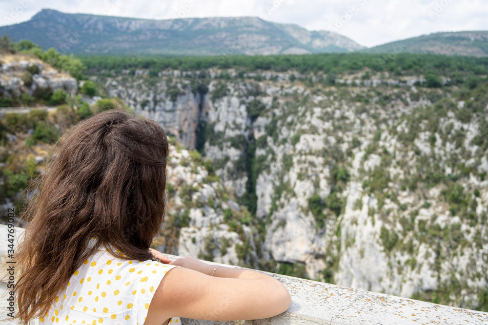 Girl is observing canyon Verdon Gorge from the bridge view to rocks in France. Girl is missing travels during this coronavirus pandemic