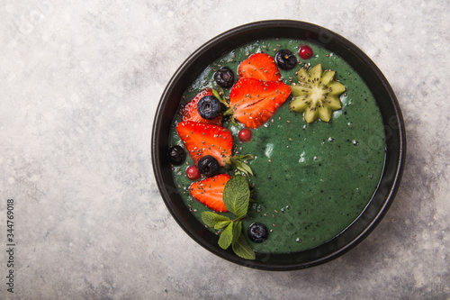 Colorful, healthy food. Acai smoothie bowl. Keto breakfast idea. Fruit curd smoothie, acai. Breakfast with green spirulina, strawberry, chia, kiwi in black plate photo