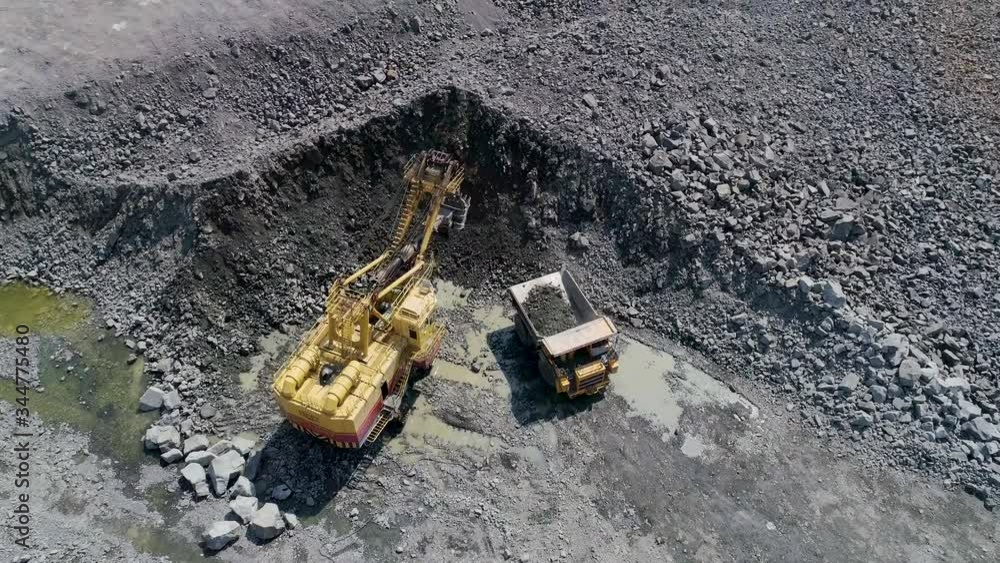 Big excavator loading granite into heavy dump truck . Heavy mining equipment operating in quarry Big excavator loading granite into heavy dump truck . Heavy mining equipment operating in quarry