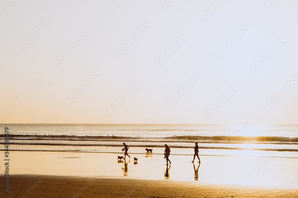 Ocean sunset, family people walking silhouettes, warm orange colour