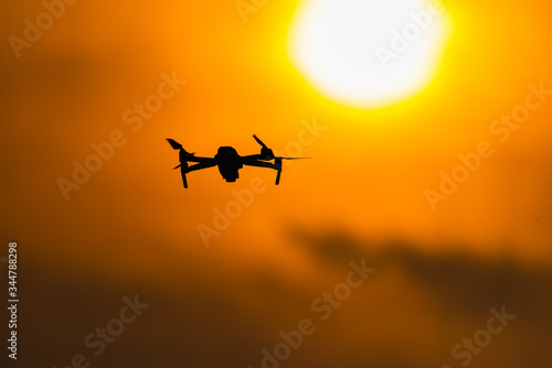 Drone flying aerial over orange sky and sun in the sunset.