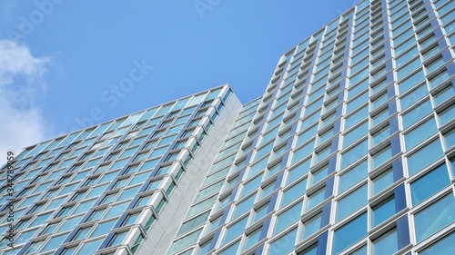 Structural glass wall reflecting blue sky. Abstract modern architecture fragment. View of a modern glass skyscraper  modern office building. Modern office facade fragment with blue glass.