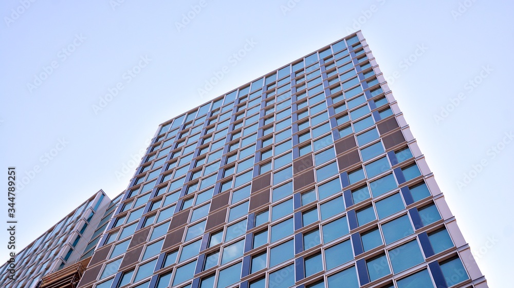 Structural glass wall reflecting blue sky. Abstract modern architecture fragment. View of a modern glass skyscraper, modern office building. Modern office facade fragment with blue glass. Structural glass wall reflecting blue sky. Abstract modern architecture fragment. View of a modern glass skyscraper, modern office building. Modern office facade fragment with blue glass.
