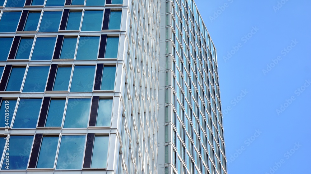 Structural glass wall reflecting blue sky. Abstract modern architecture fragment. View of a modern glass skyscraper, modern office building. Modern office facade fragment with blue glass. Structural glass wall reflecting blue sky. Abstract modern architecture fragment. View of a modern glass skyscraper, modern office building. Modern office facade fragment with blue glass.