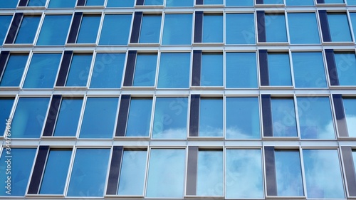 Structural glass wall reflecting blue sky. Abstract modern architecture fragment. View of a modern glass skyscraper, modern office building. Modern office facade fragment with blue glass.