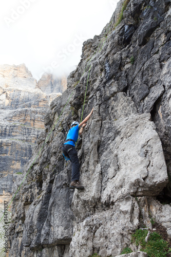 Man doing rock climbing with rope in Brenta Dolomites mountains, Italy