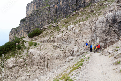 People hiking in Brenta Dolomites mountains during rain, Italy