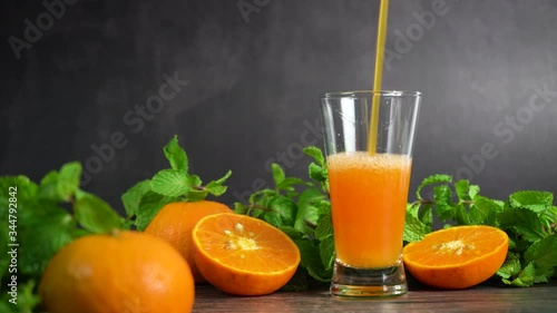 Pouring fresh orange juice into a glass with oranges fruit and peppermint on table, Healthy food.