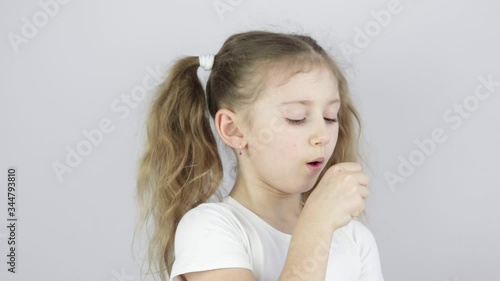 little girl coughs covering her mouth with her fist, the concept of morbidity, infection, colds.
