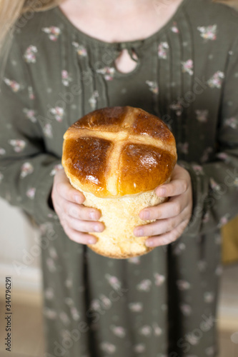 Traditional Easter Hot Cross Buns. Little girl holding round bread. Hands holding big bread. Little girl holding Easter Cross Buns. Hands holding Easter Cross Buns.