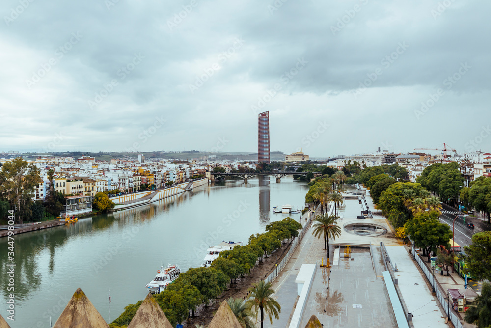 Obraz premium Panoramic of Seville with the Guadalquivir River and the Seville Tower in the background with cloudy sky.