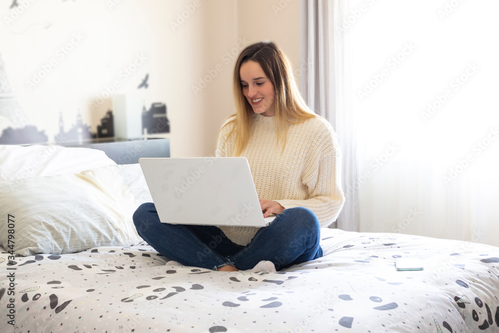Photography of a woman teleworking in her bed from home smiling. Coronavirus quarantine. Remote working woman. Photography of a woman teleworking in her bed from home smiling. Coronavirus quarantine. Remote working woman.
