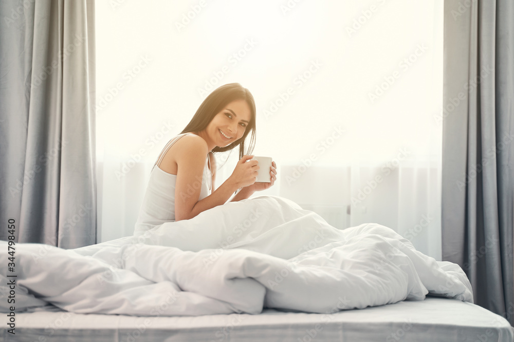 Positive delighted brunette girl sitting under blanket Positive delighted brunette girl sitting under blanket