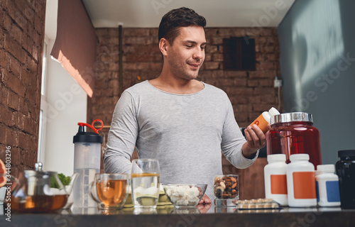 фотографія Fit man examining a dietary supplement in his hand