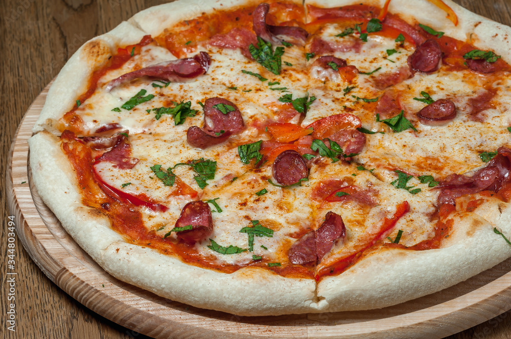 pizza on a wooden tray stands on a wooden table pizza on a wooden tray stands on a wooden table