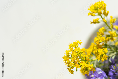 Spring flowers in a vase top view. Beautiful yellow and purple flowers in a glass vase. Flowers on a white background