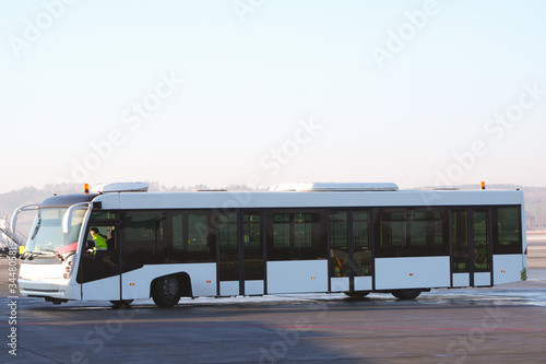 White passenger shuttle bus of the airport servise is driving along the runway at the airport. organization of traffic on the runway, airport control service. airport transfer bus photo