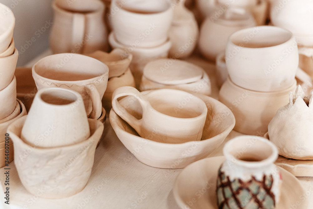 Raw ceramic pottery kitchenware drying on the shelf. Art workshop concept Raw ceramic pottery kitchenware drying on the shelf. Art workshop concept