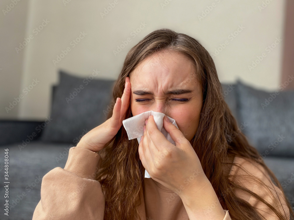 Cute girl sitting on the sofa, holding her head has a severe headache. Cute girl sitting on the sofa, holding her head has a severe headache.