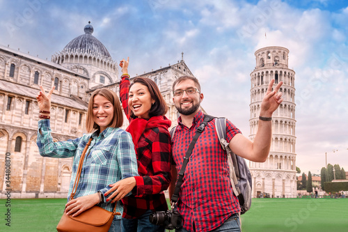 Photographie A fun and diverse group of young tourist friends pose against the backdrop of the famous leaning tower in Pisa