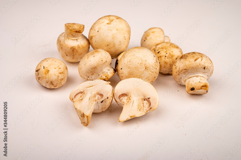 Halves of cut young mushrooms and young mushrooms scattered on a white background. Close up. Halves of cut young mushrooms and young mushrooms scattered on a white background. Close up.