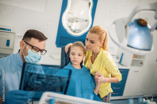 Dentist and female patient looking to x-ray