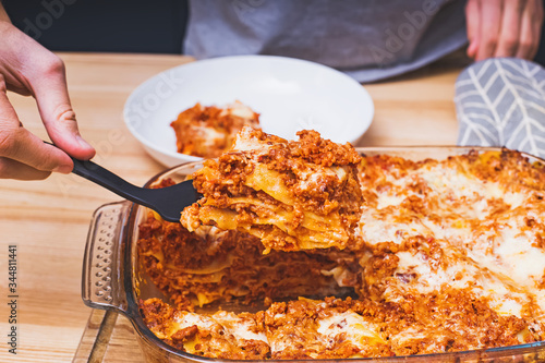Man hand close-up taking a piece of delicious homemade lasagna