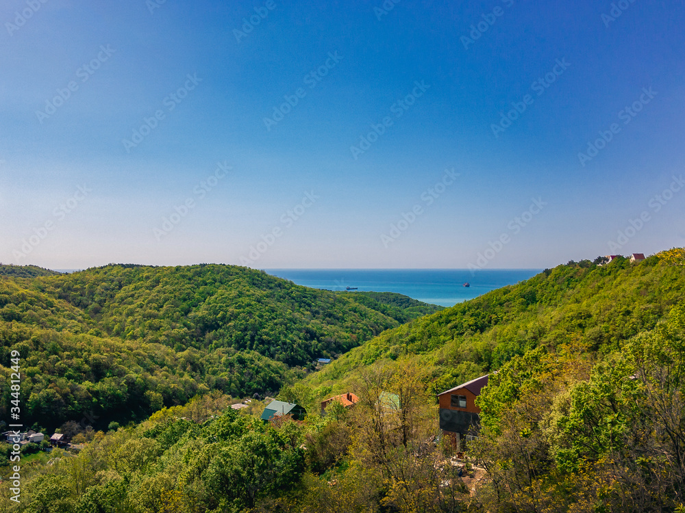 Beautiful view of the mountains covered with green vegetation against the blue sky and sea on the horizon.