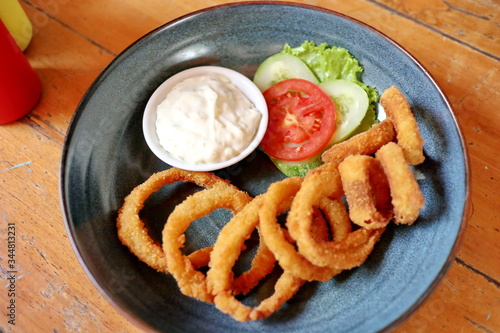 Unfocused, Blurry selective focus image fried onions with flour or onion ring, served with mayonase sauce, cucumber and tomatoes.   photo