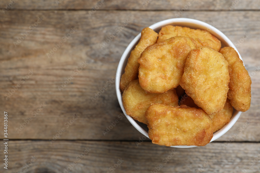 Bucket with tasty chicken nuggets on wooden table, top view. Space for text Bucket with tasty chicken nuggets on wooden table, top view. Space for text